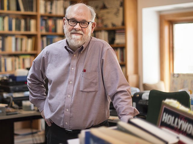 Photo of David Bordwell standing in an office filled with books